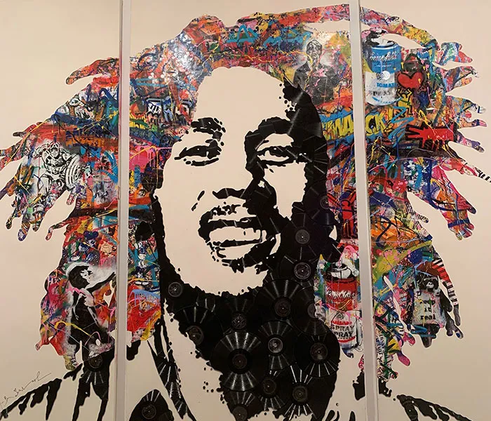 A collage of colorful pieces forms a portrait of a man with dreadlocks against a white background.