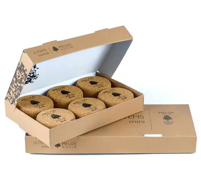 Open cardboard box containing six round cork items, labeled 